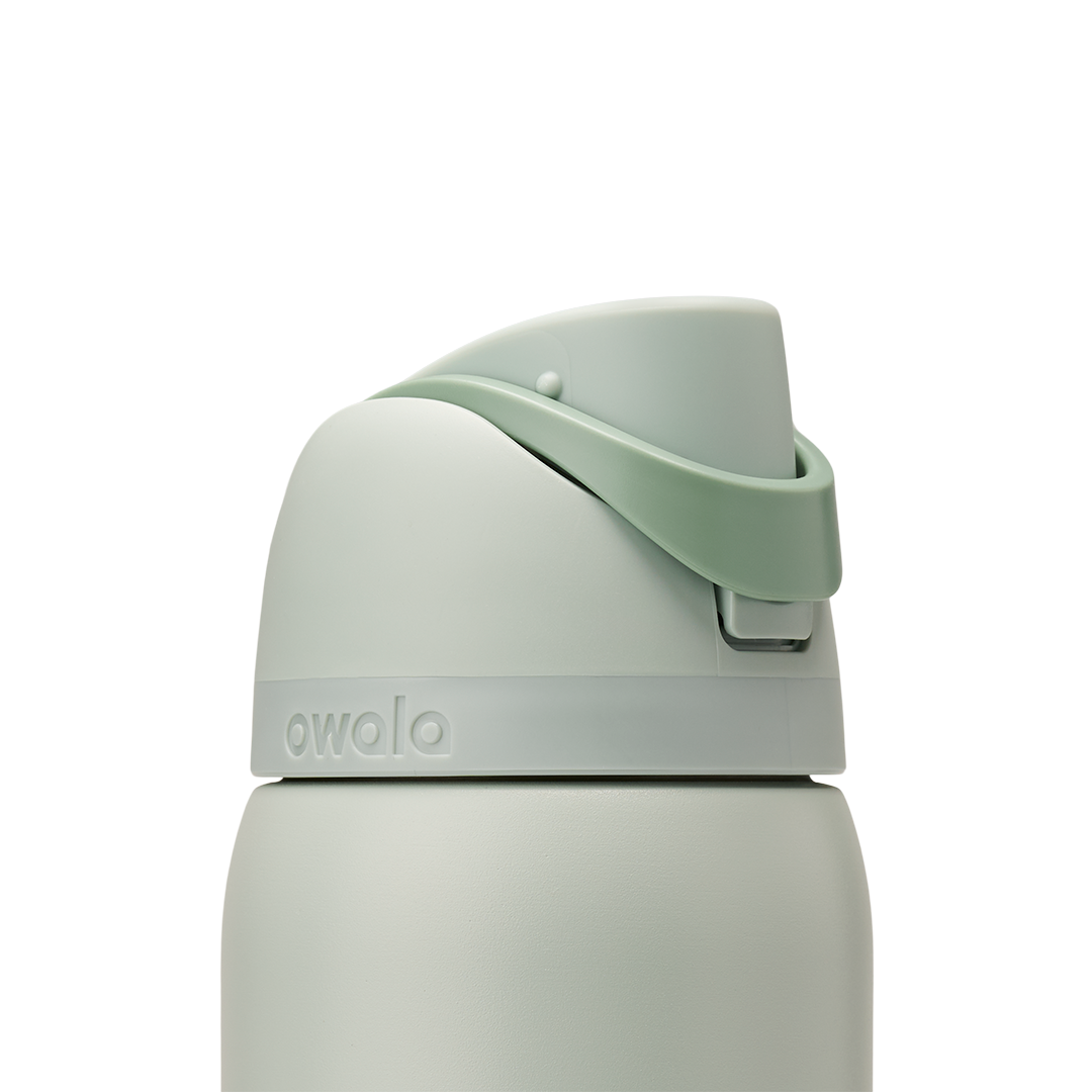 Owala FreeSip 32oz in Summer Paradise, lid detail showing sage green flip cap closed with mint green carry loop arched over the top and embossed accent band at the lid base